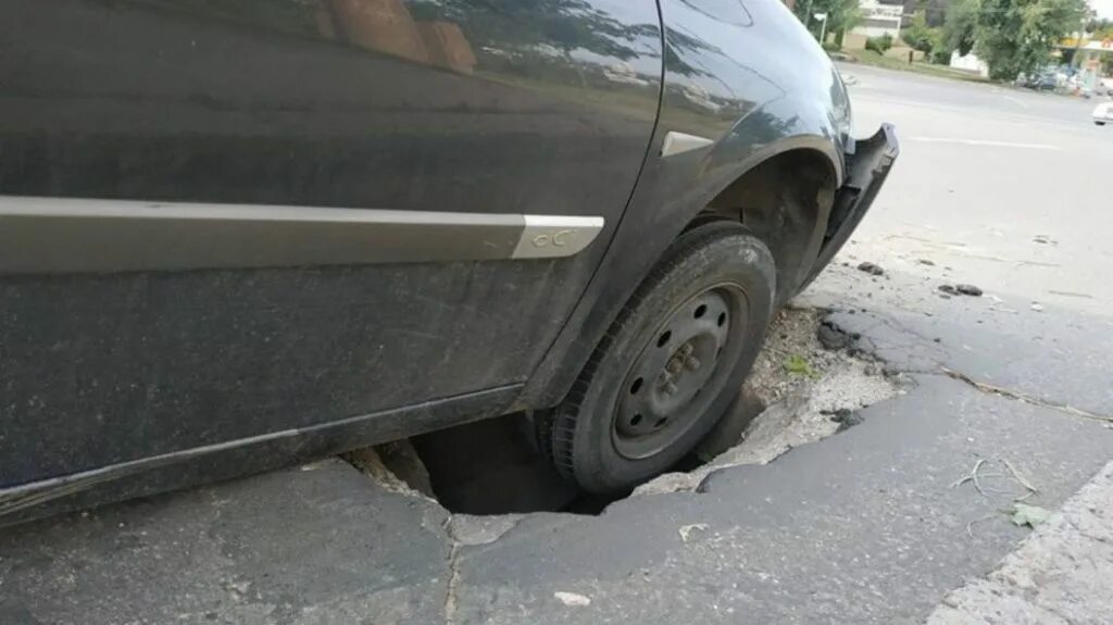 Чем грозят плохие. Автомобиль попал в яму на дороге. Колесо в яме на дороге. Повреждение автомобиля.