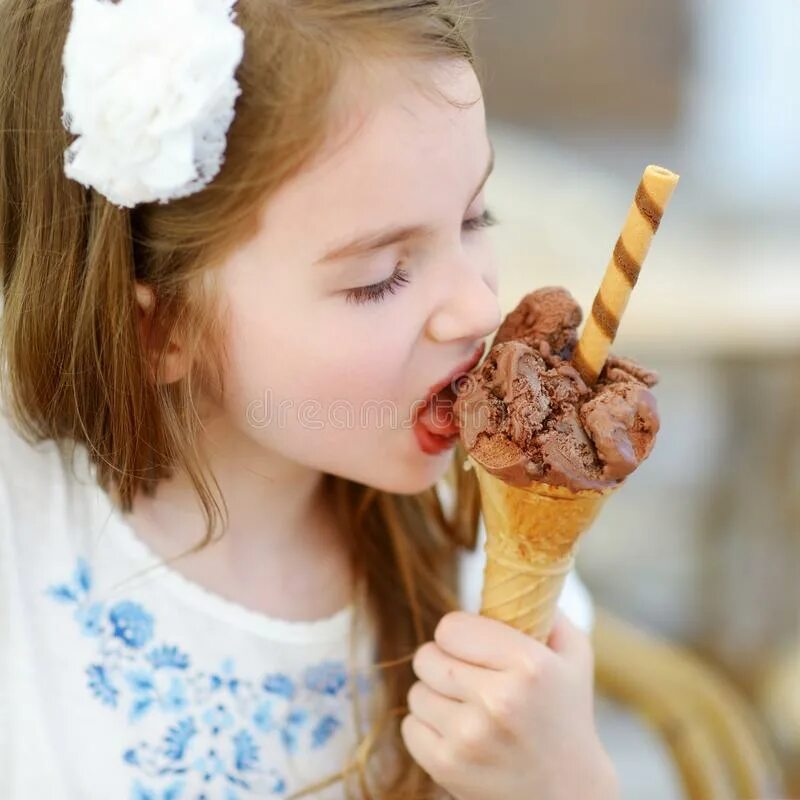 Маленькая девочка и мороженое. Маленькая девочка ест мороженое. Маленькая девочка облизывает мороженое. Ребенок облизывает мороженое.