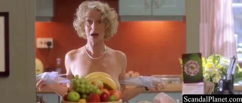 Helen Mirren stands naked in front of an apple press. 