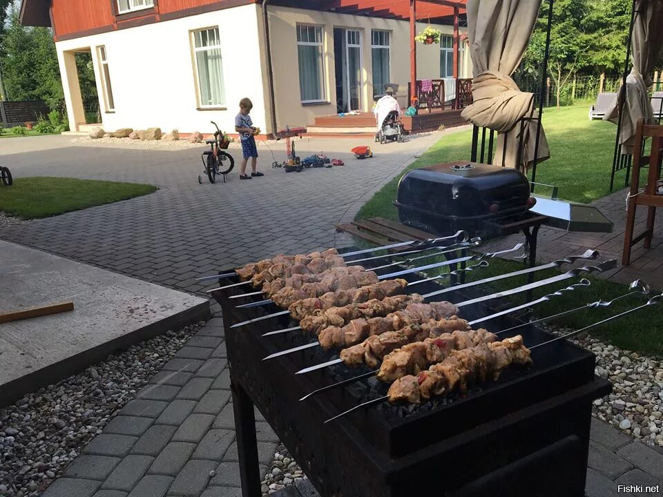 Жарят шашлык во дворе дома. Шашлыки. шашлык на мангале. шашлыки на даче. барбекю во дворе.