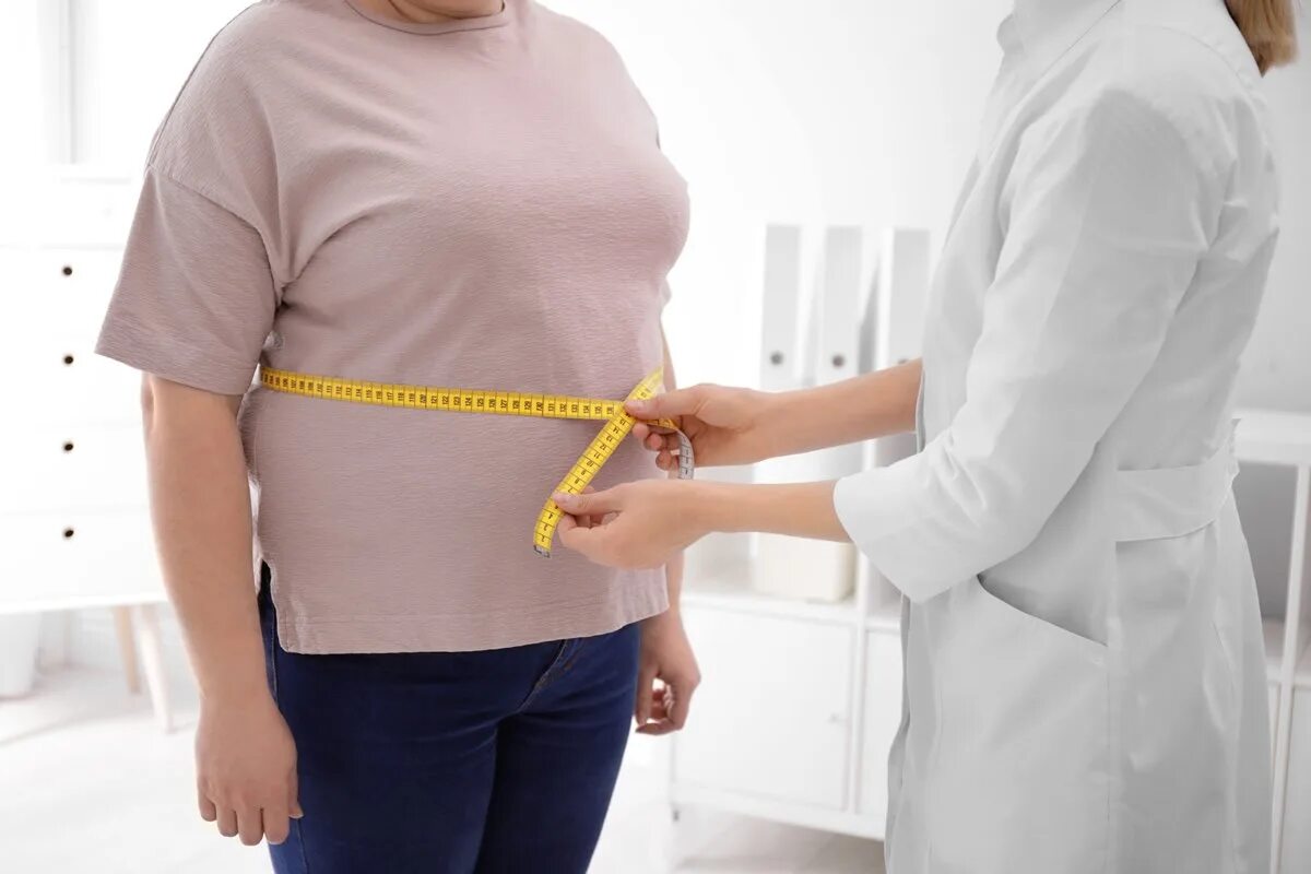 Лишний вес у женщин после 50. Врач меряет талию. Измерение окружности талии. Ожирения измерение талии.