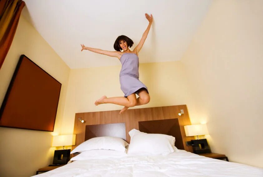Как узнать в постели. Прыгать на кровати. Прыгать на кровати в отеле. Девочка прыгает на кровати. Человек прыгает на кровати.