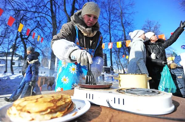 Дети пекут блины на масленицу. Блины на улице Масленица. Печём блины на Масленицу. Масленица пекут блины. Угощение блинами на Масленицу.