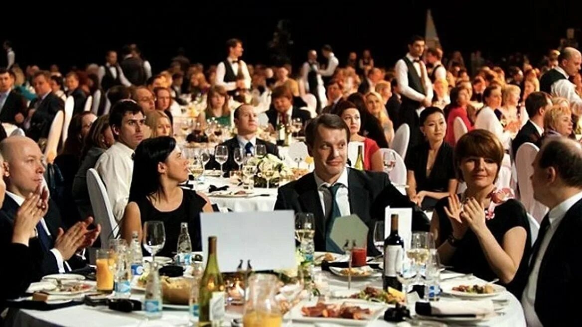 Человек оратор. Мужчина за столом. Полный зал. Полный зал аплодисменты. Публика в театре.