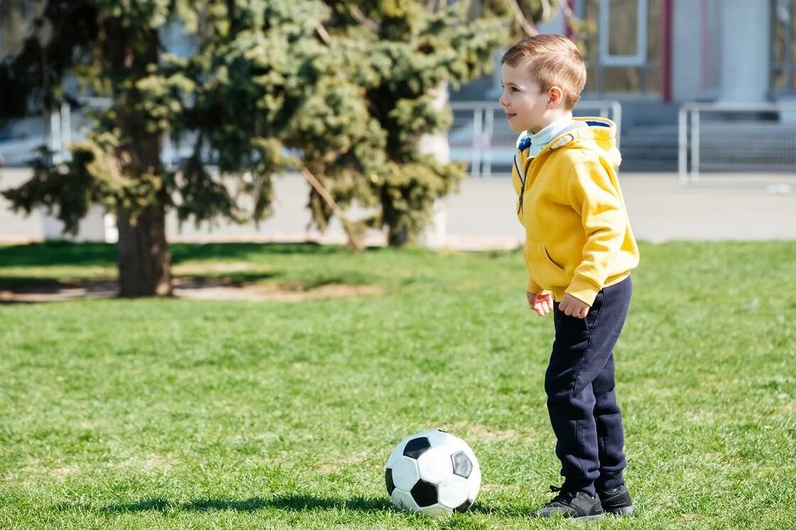 Look is playing football. Вид спорта футбол. Дети бегут по футбольному полю. Футболисты. Футболист в движении.