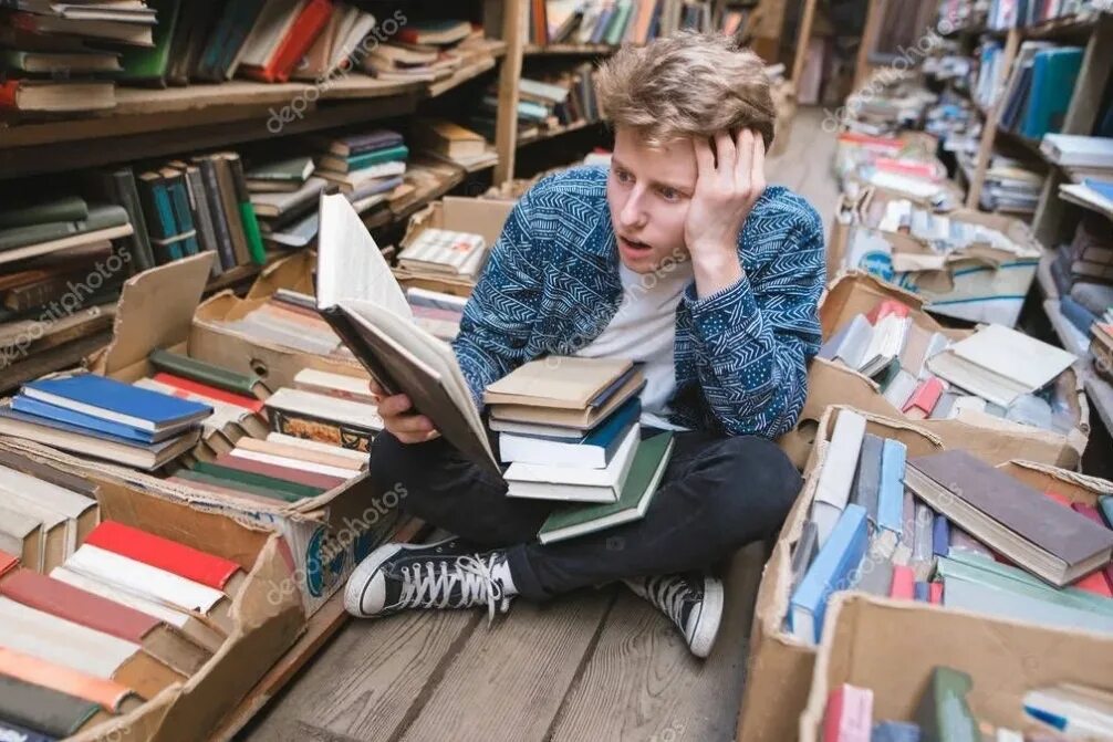 Выглядит читать. Человек заваленный книгами. Сидит за книгами. Люди в библиотеке. Студенты в библиотеке.