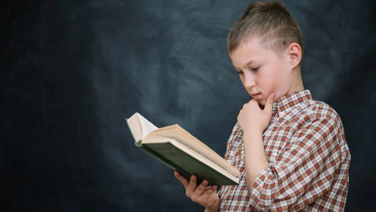 Ученики держат книгу. Школьник держит. Мальчик стоящий рядом с книгами. Мальчик стоит на книгах.