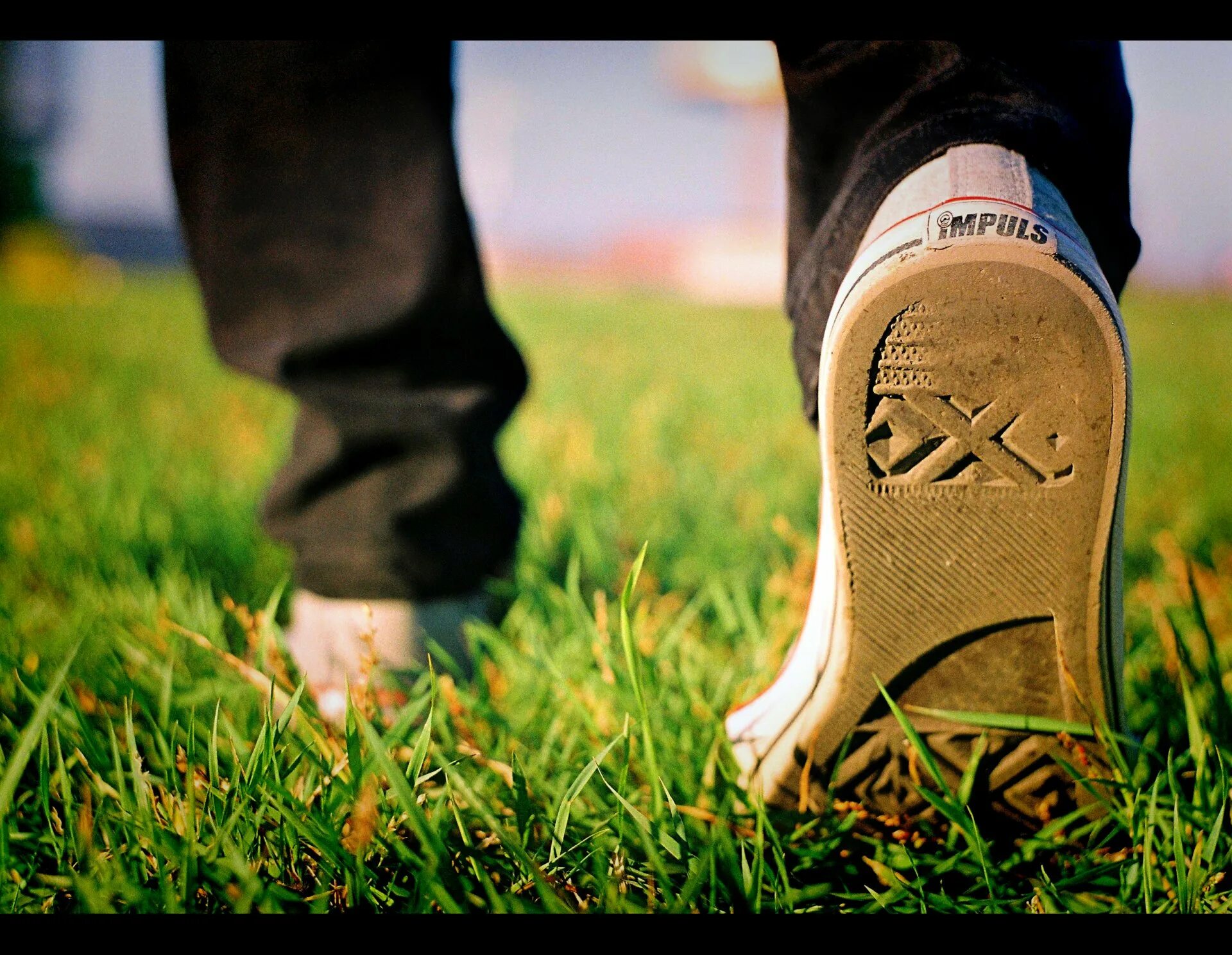 Наступить на порог. Ноги на траве. Шаг человека. Ботинки в траве. Обувь на земле.