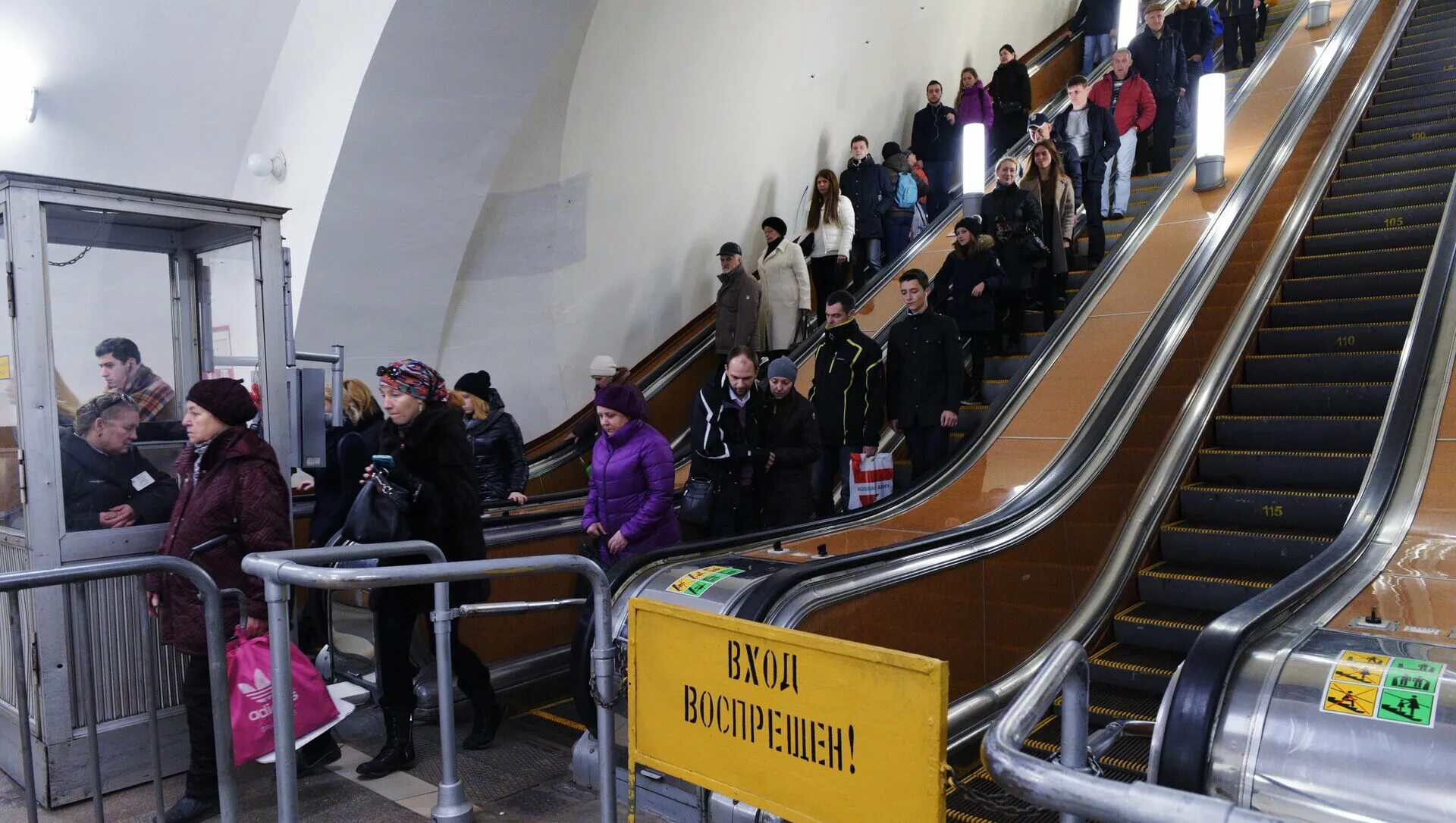 Эскалатор метрополитена поднимает стоящего. Люди на эскалаторе в метро. Человек спускается в метро. Пассажиры спускаются в метро на эскалаторах. Спуститься в метро на эскалаторе.