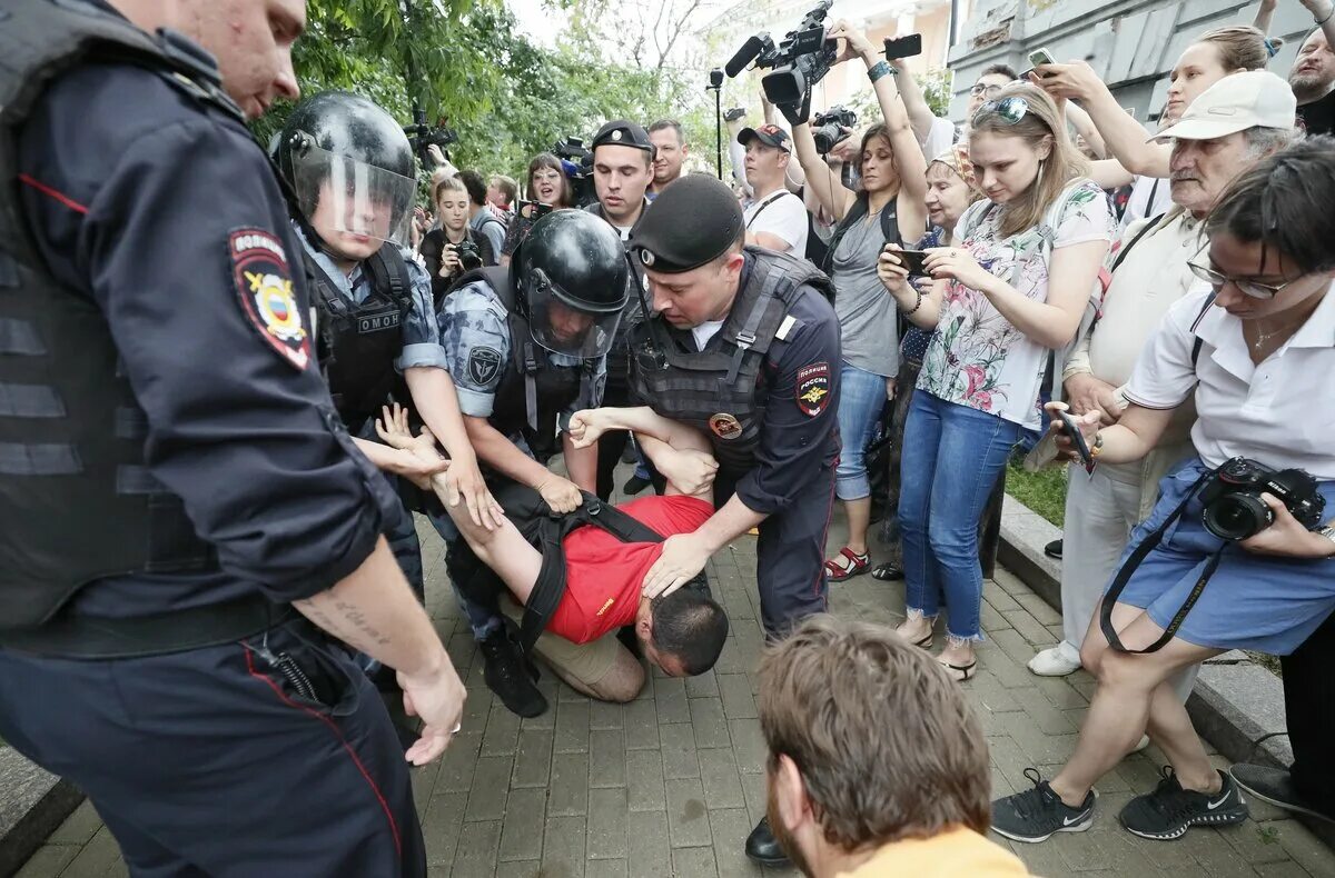 Полицейские на митинге в Москве. Полицейский избивает человека. Сотрудники на митинге