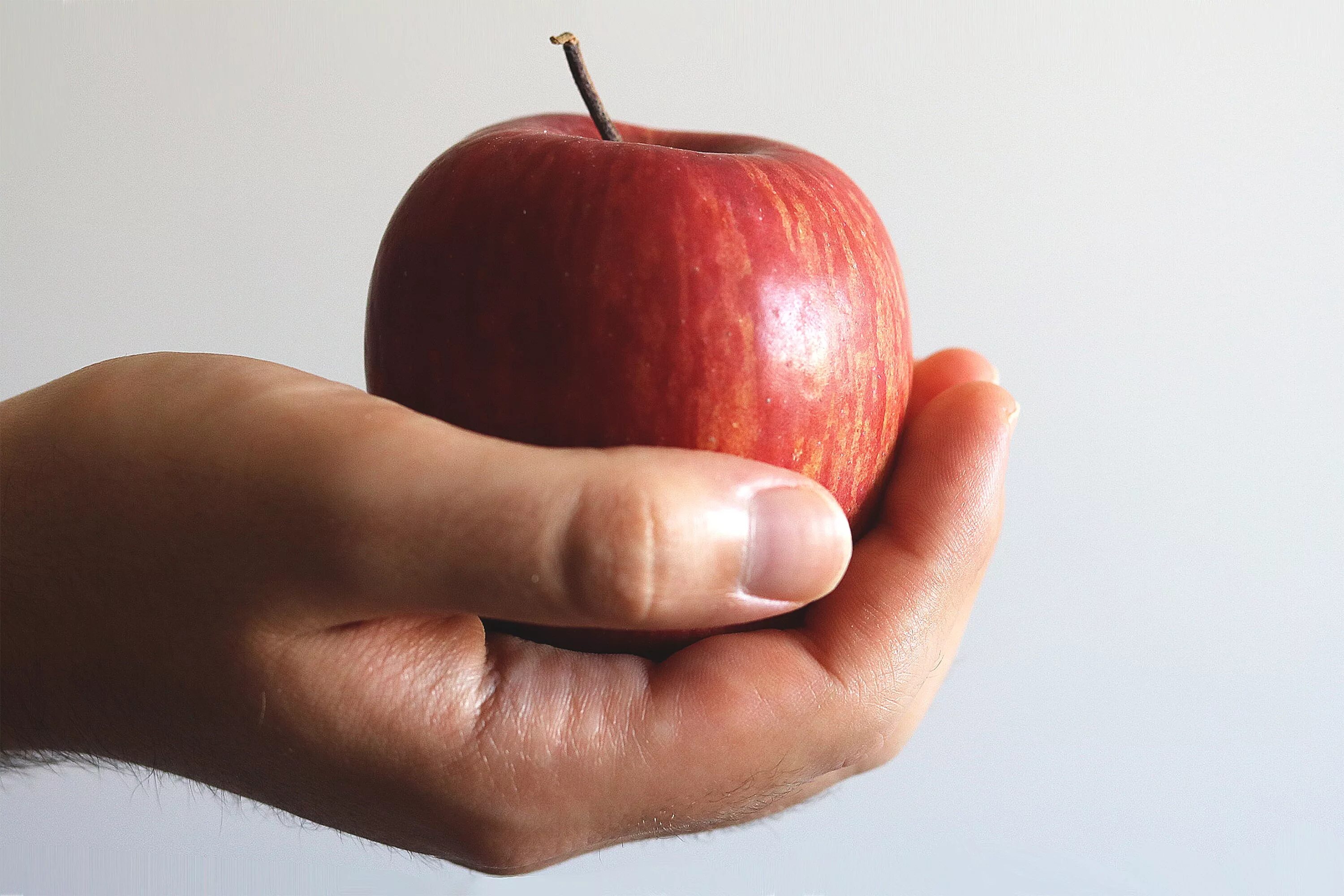 Яблоко. Яблоко в руке. Рука держит яблоко. Яблоки красные.