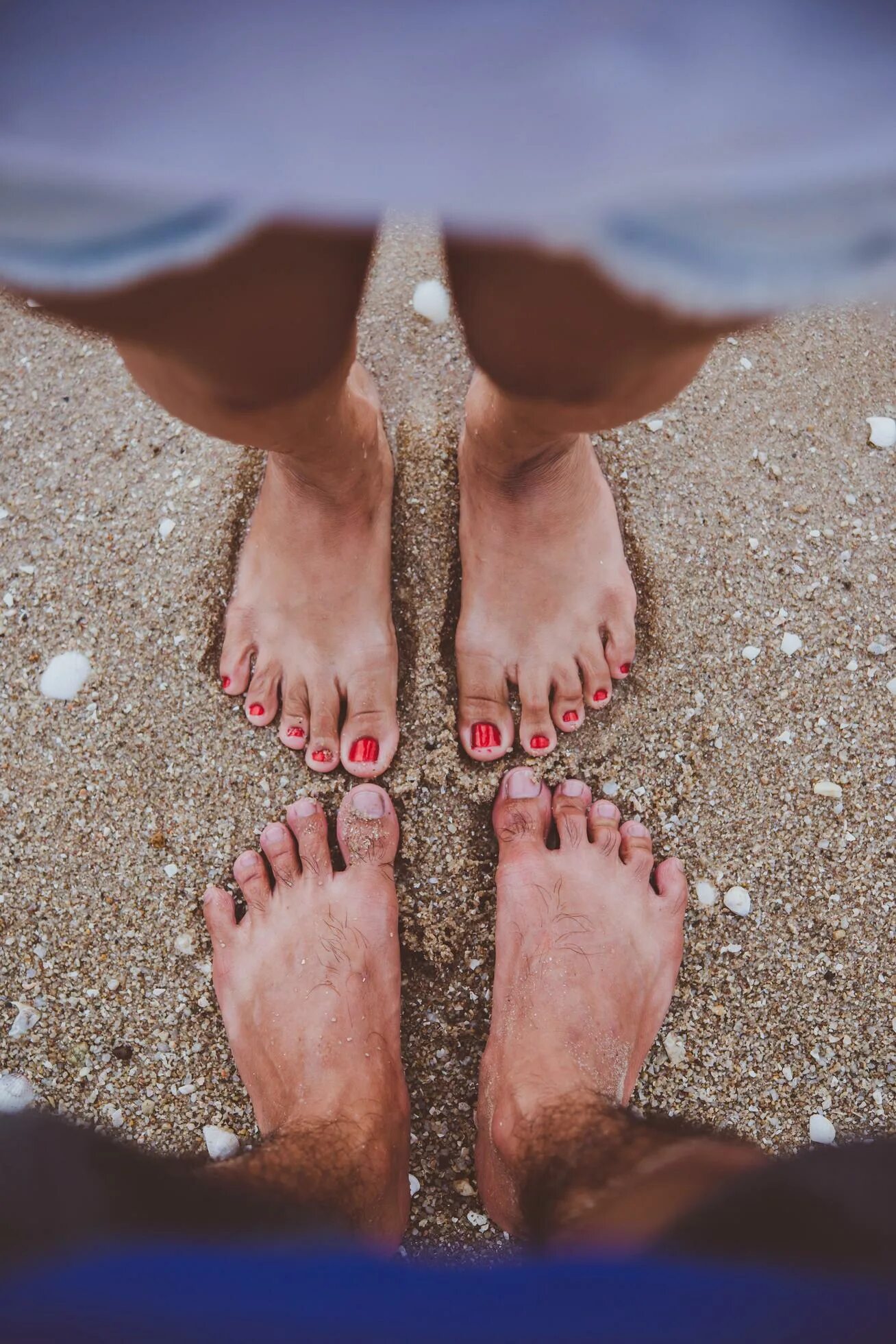 Couples feet. Ступни пары. Стопы вместе. Ноги молодой пары на пляже. Четыре пары ног на пляже.