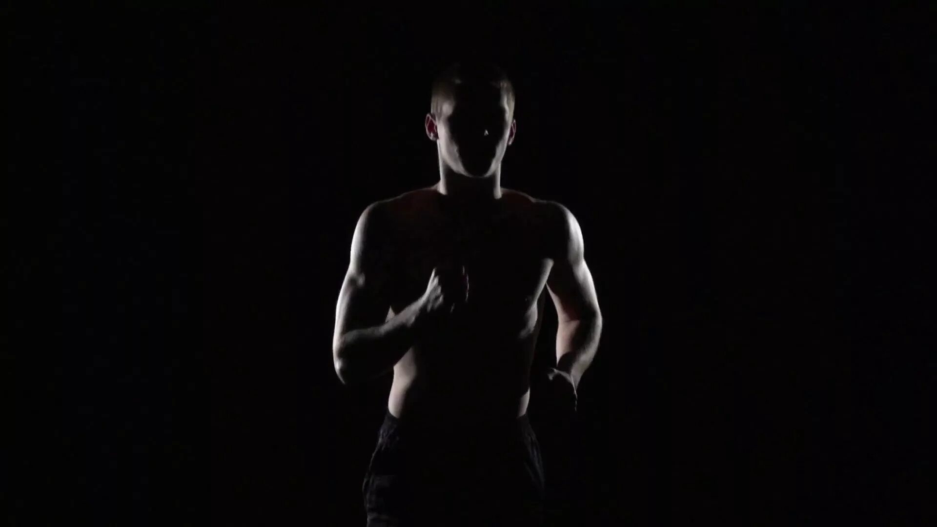Качок в темноте. Спортсмен в темноте. Бег на черном фоне. Тень мужчины. Мускулы мужские в темноте.