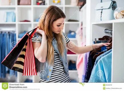 Молодые женские Shopaholic держа хозяйственные сумки и дамы выбирать носят ...