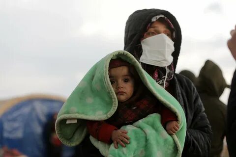 A woman carrying a baby watches as search and rescue operations continue da...