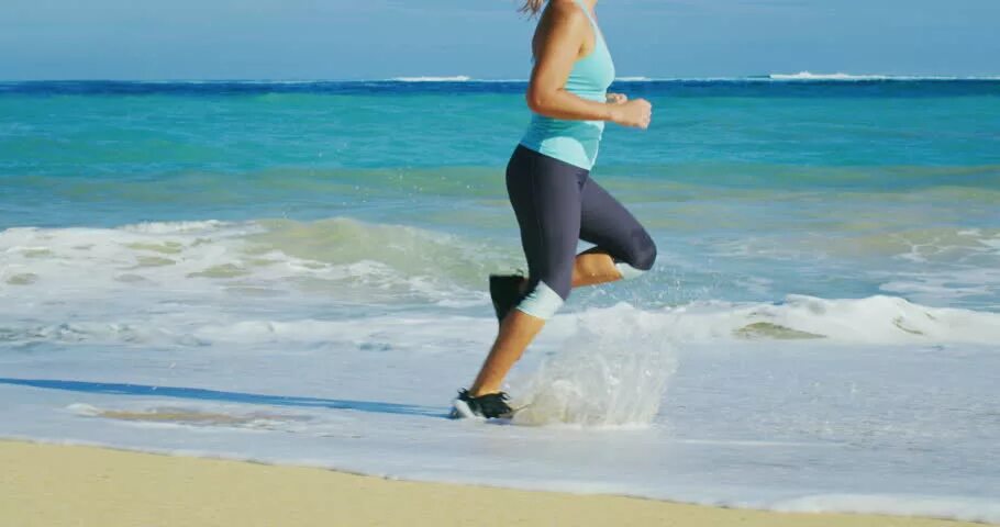Бег у моря. Девушка в спортивном костюме бежит у моря. Девушка в спортивном белом костюме бежит у моря.