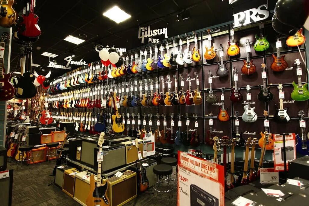 В музыкальном магазине продают скрипки и гитары. Гитарный магазин. Гитары музыкальные магазины. Гитарный центр. Магазин электрогитар.
