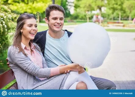Young Couple Strolling In The Park And Eating Cotton Candy Stock Photo.