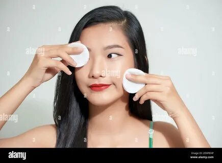 Healthy fresh asian girl removing makeup from her face with cotton pad smil...