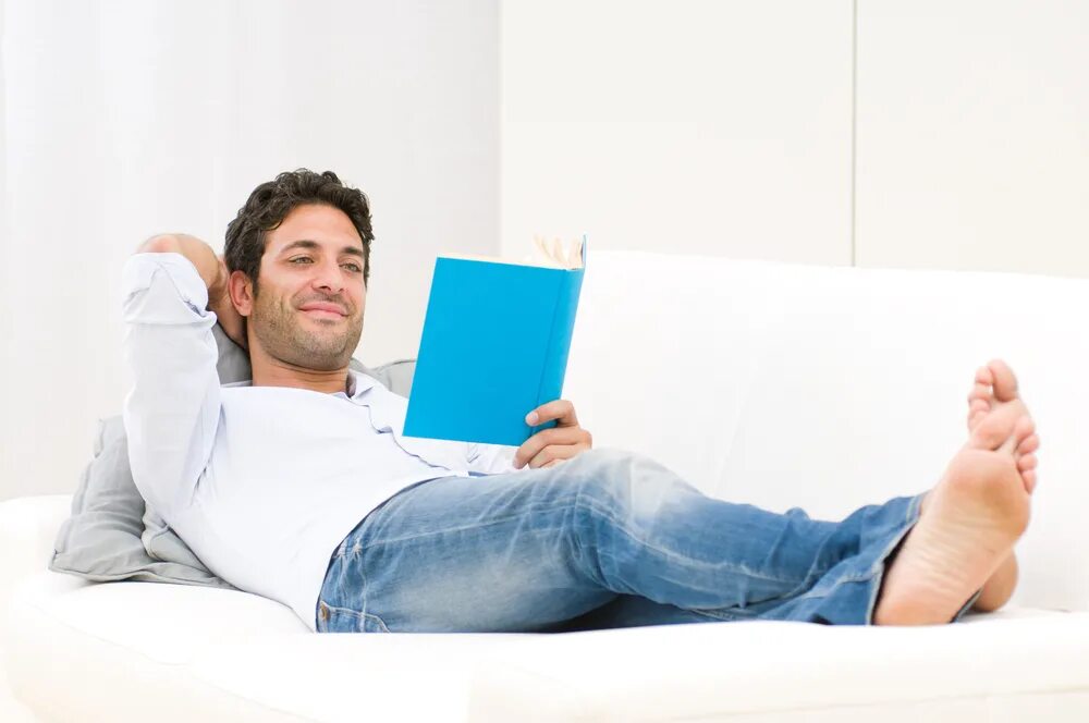 Человек на диване с книгой. Мужчина на диване с книгой. Человек лежит на диване с книгой. Мужчина лежит на диване с книгой. Rest man