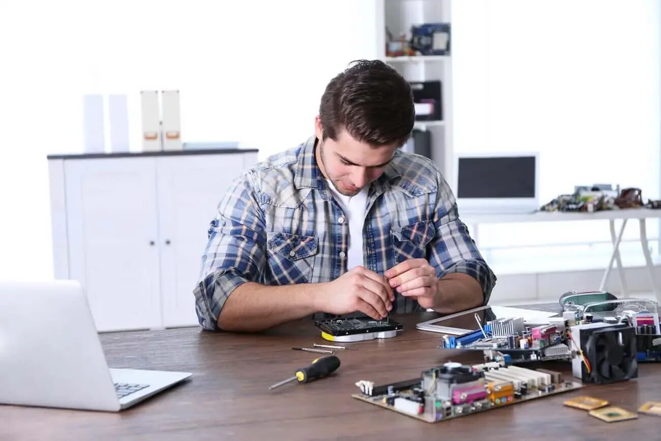Человек чинит часы. Починка интернета. Человек ремонтирует за столом. Процесс ремонта компьютера.