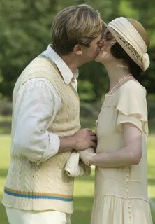 a man and woman kissing each other in front of trees 