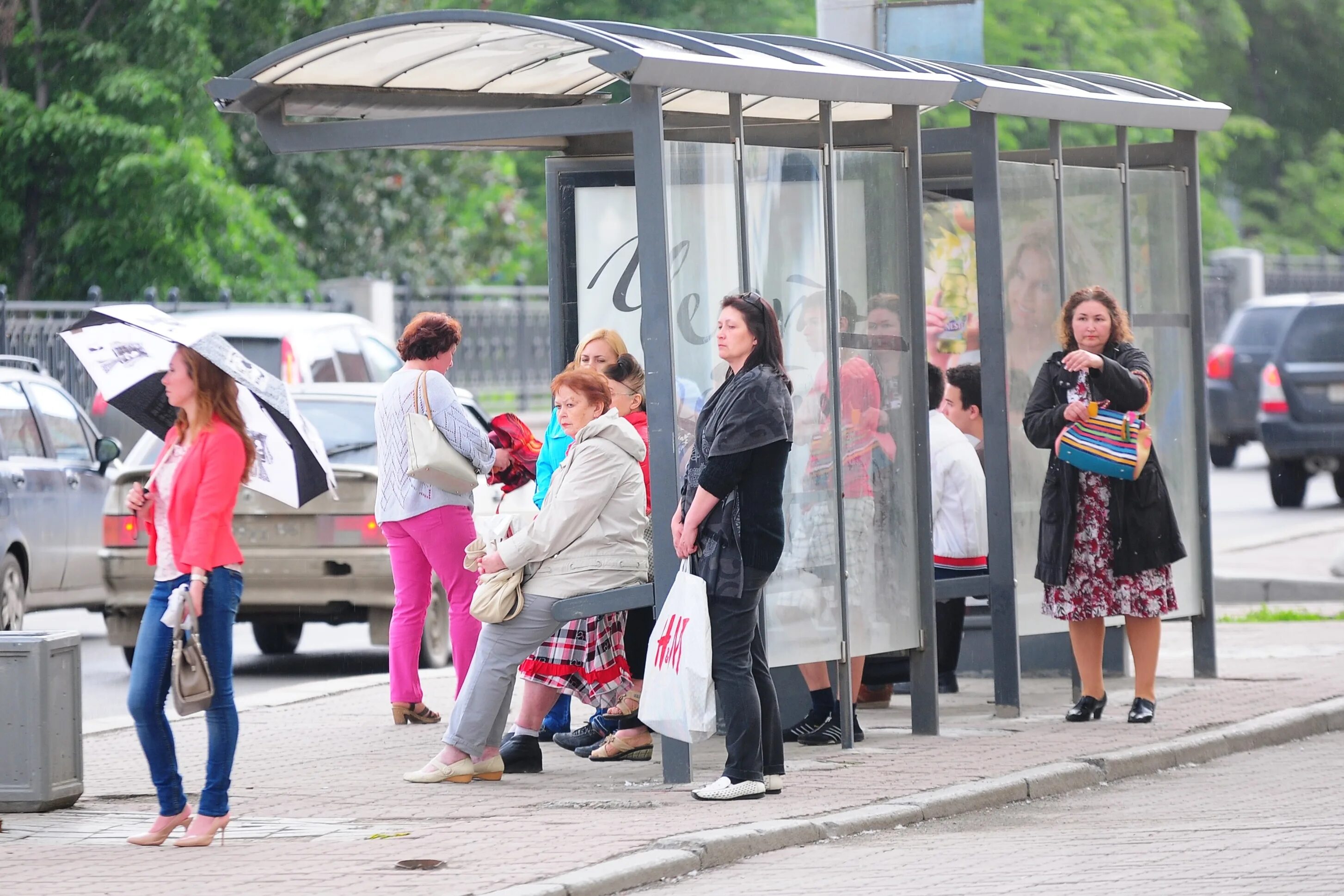 Люди ждут автобус на остановке