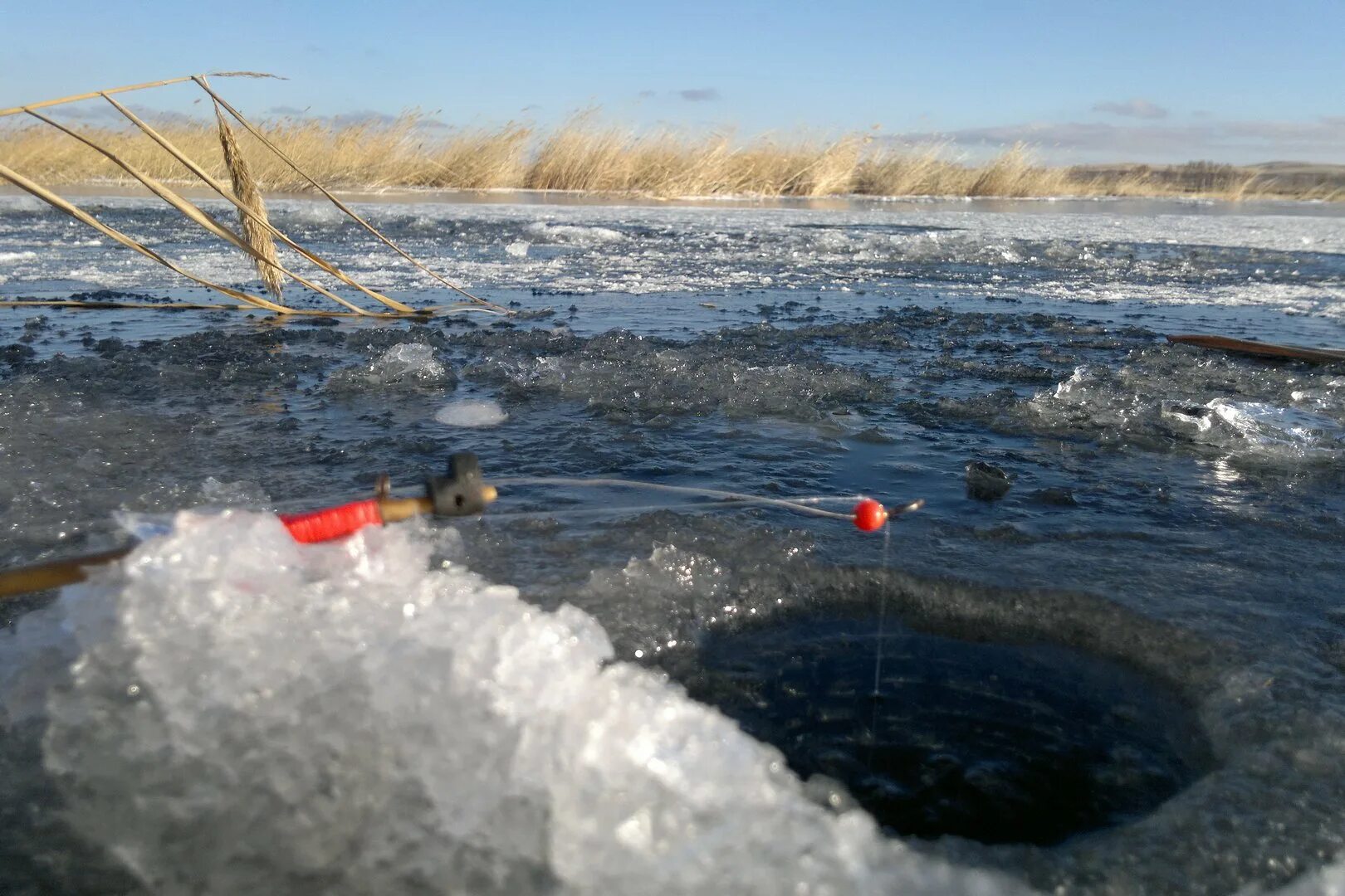 самый первый лед. первый лед на лужах. рыбаки на льду. самый первый лед. первый лед на озере.