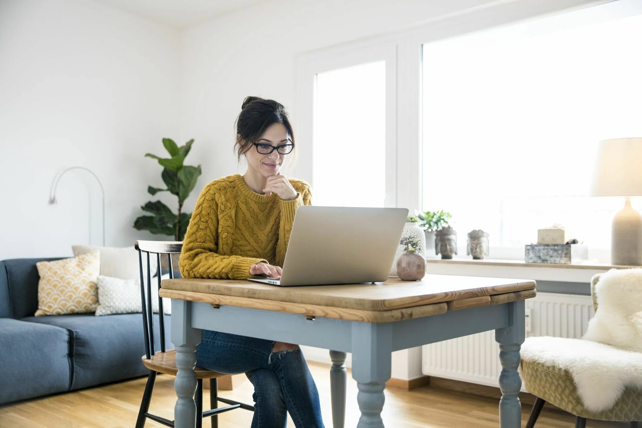 A window next to the table. Место для одного человека за столом. woman sitting at the table working. alone with workers. home office work at home.