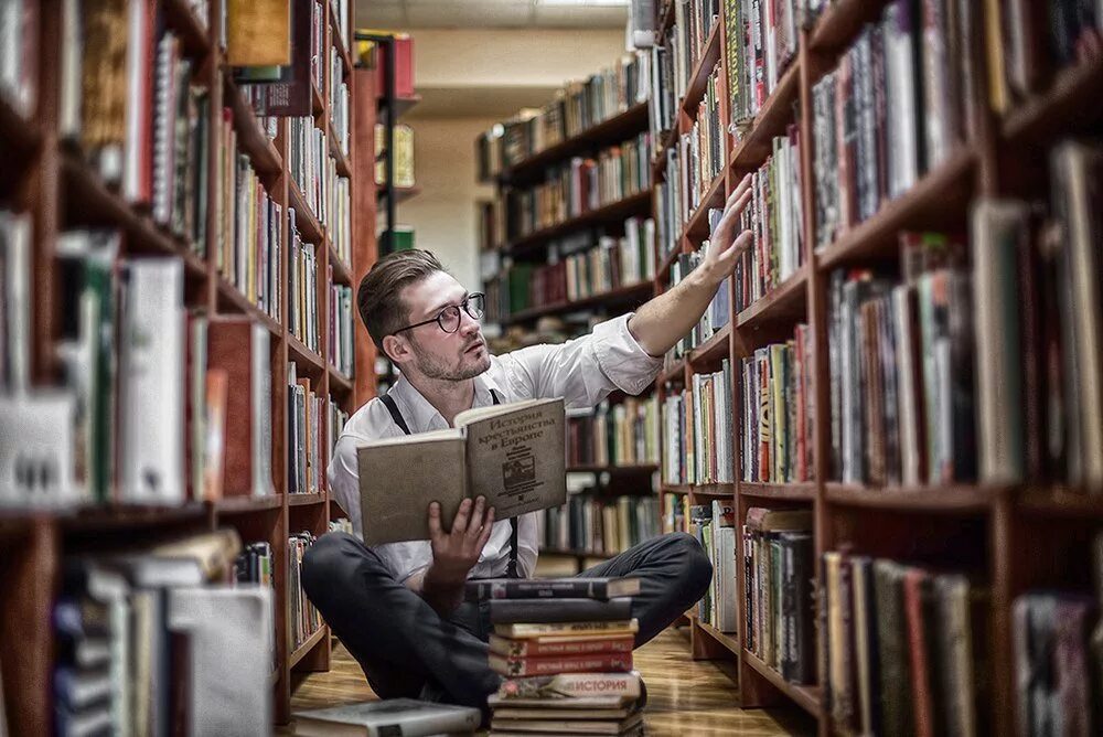 Чтение книг в библиотеке. Люди в библиотеке. Читает книгу. Библиотекарь мужчина. Чтение в библиотеке.