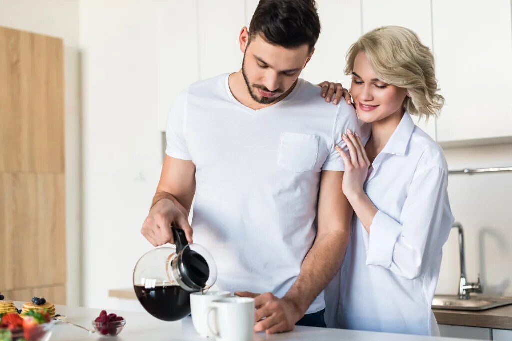 Попить на кухне. Женщина и мужчина пьют кофе на кухне. Парень и девушка на кухне пьют кофе. Пара пьет кофе на кухне. Женщина пьет кофе на кухне.