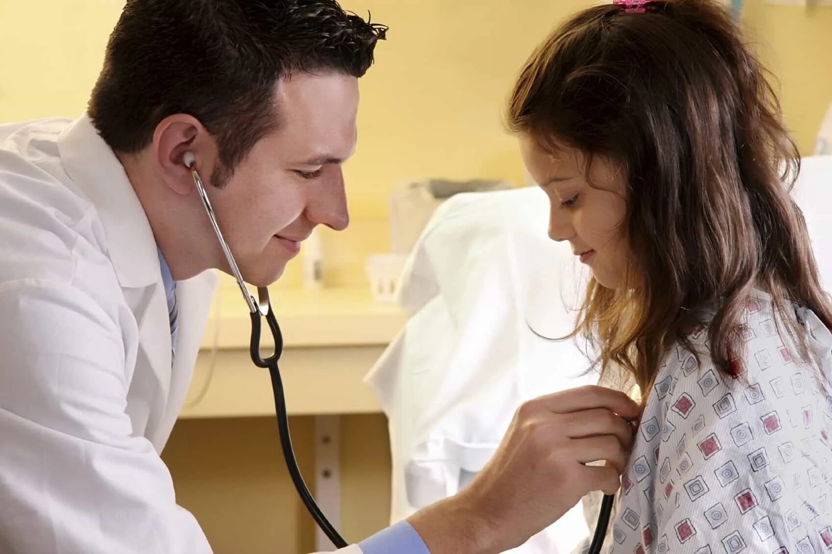 Фельдшер осматривает больного. Фельдшер слушает. Фельдшер слушает. Фельдшер слушает стетоскопом. Подросток у врача.