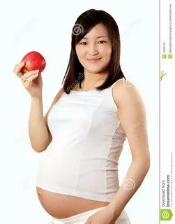 Молодая супоросая азиатская женщина демонстрируя здоровый выбор заедк.