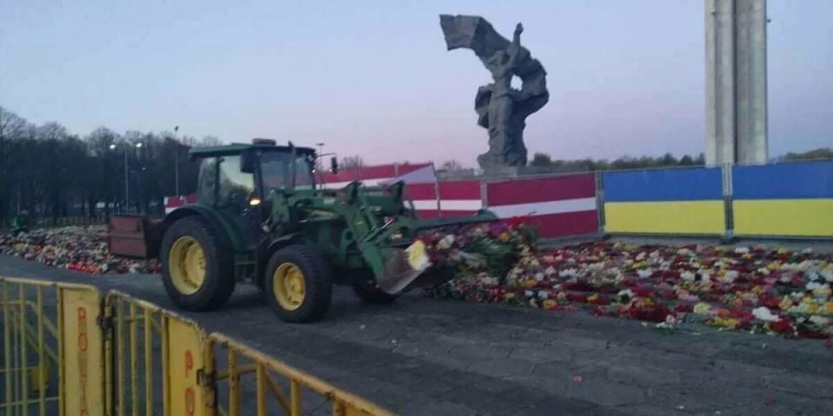 Памятник воинам освободителям в Латвии. Трактор в цветах. Бульдозером сносят цветы. Памятник освободителям Риги. Тракторный маи