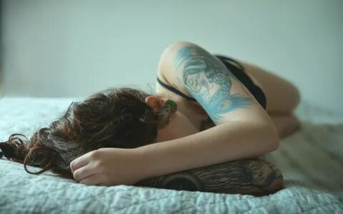 Девушка с татуировкой лежит на спине