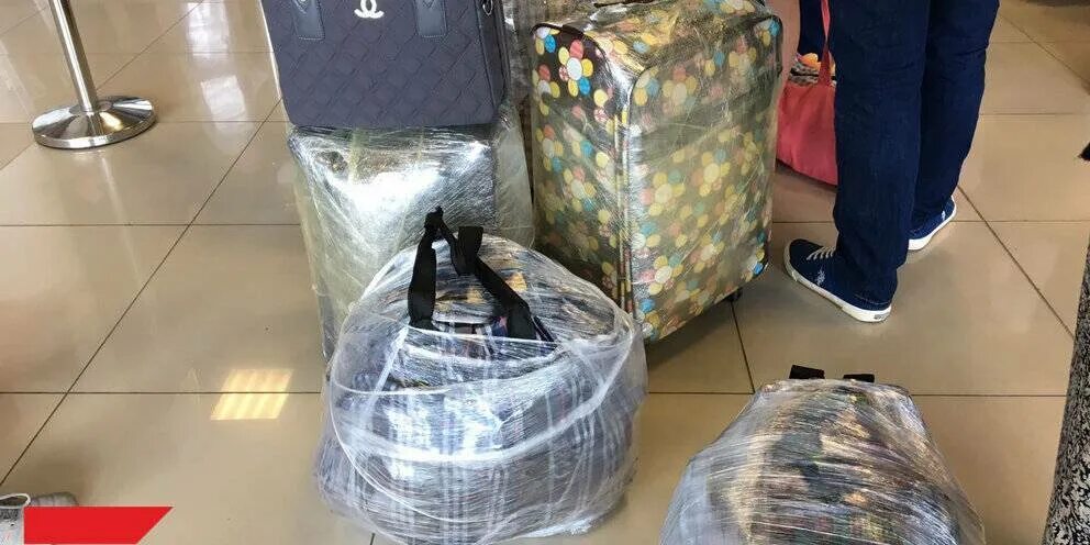 Упаковка сумки в аэропорту. Упаковка дорожной сумки в аэропорту. Упаковать чемодан в пленку. Упаковка чемодана в пленку.