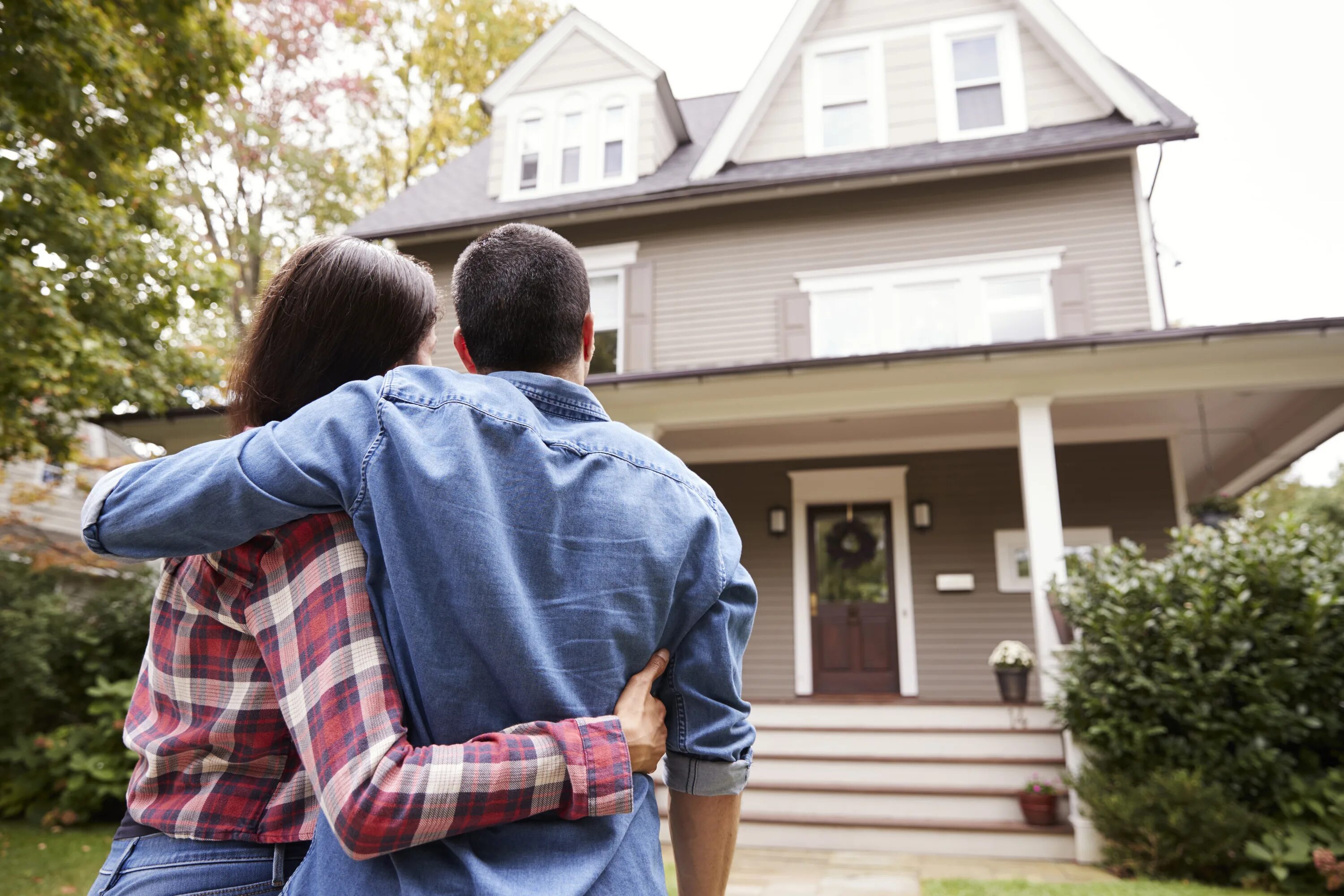 They bought a new house. Мужчина рядом с домом счастливый. Счастливая семья в доме. Семейная пара со спины. Человек смотрит на дом.