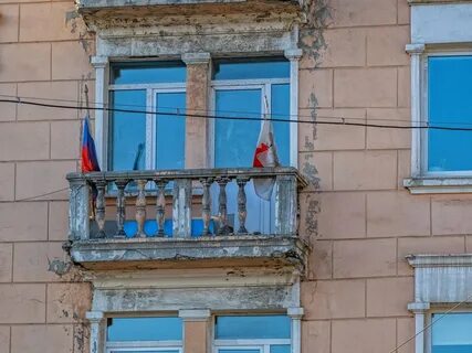 Вешает флаг на балконе