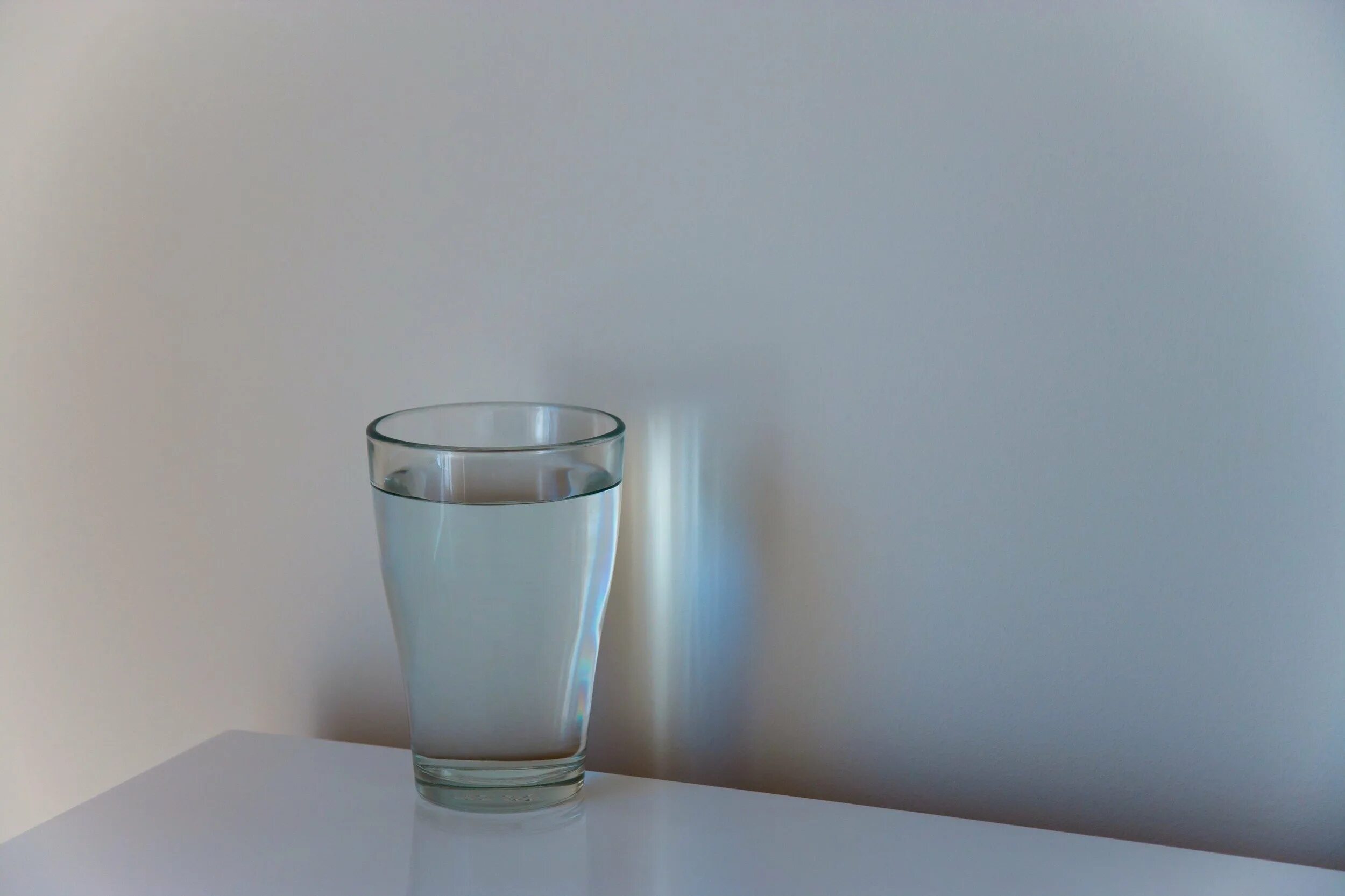 Стакан воды. Стакан воды на столе. Стакан на столе. Прозрачный стакан с водой на столе. Взвесь в стакане воды
