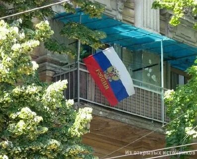 Вешает флаг на балконе