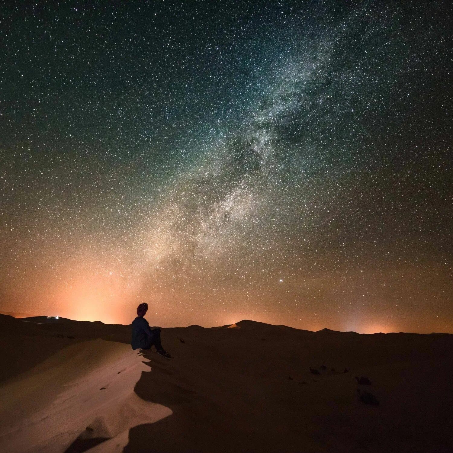 Tourist on top of a mountain enjoying night sky view with stars фотография Stock