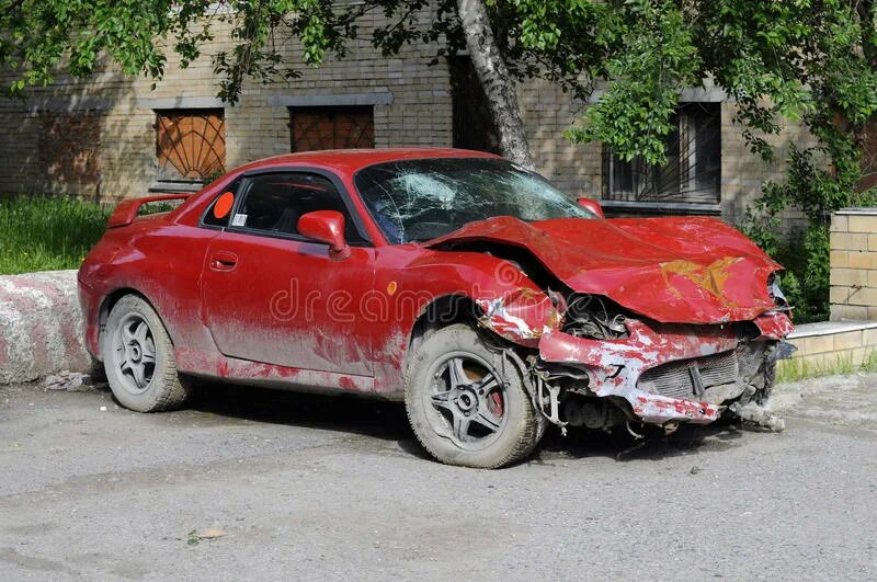 Разбитый красный автомобиль.