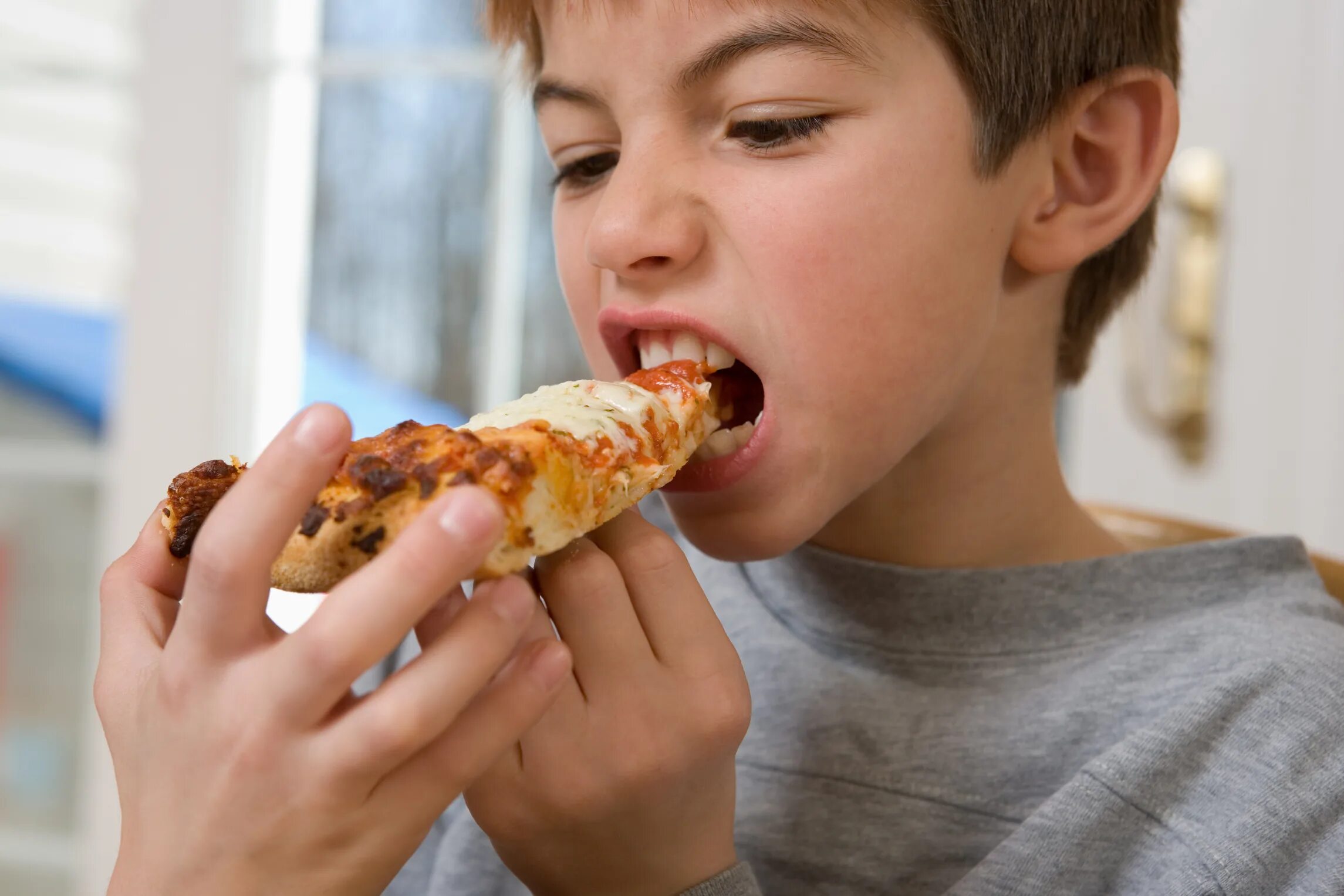 мальчик обедает. He is eating. обгрызанная пицца. He is eating. еда для детей.