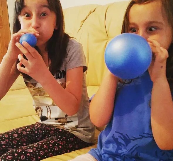 Balloon blowing up. Girl blowing up balloon. blow up balloons. two girls blow large purple balloons.
