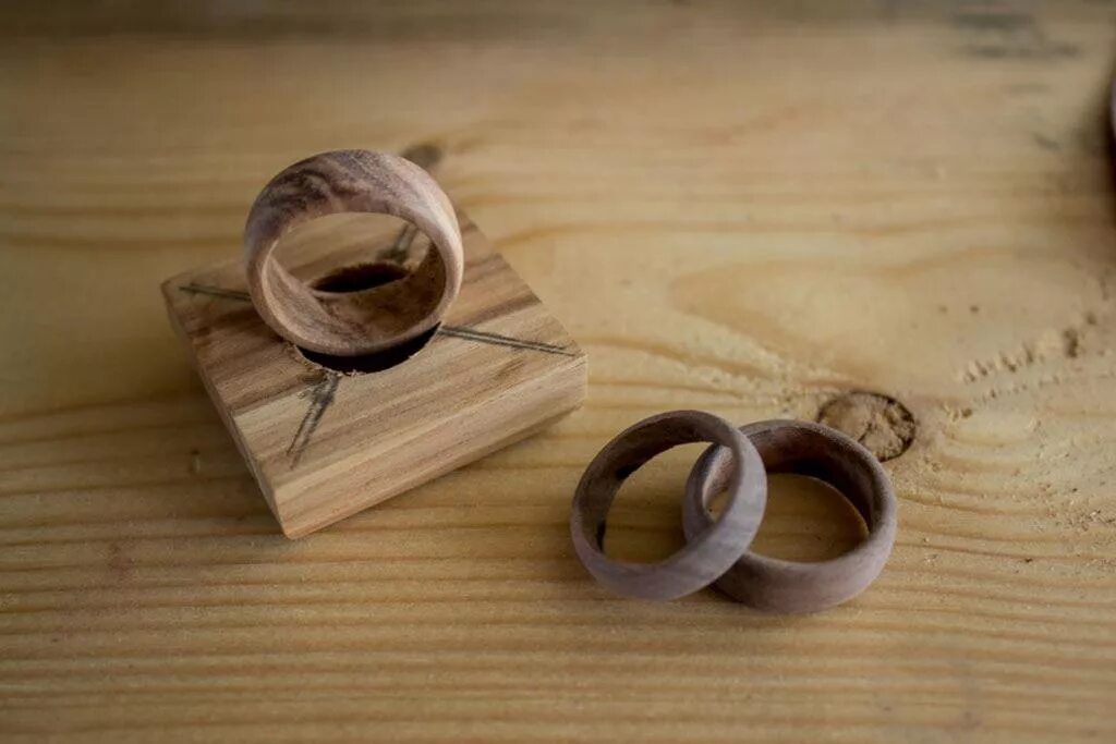 Из какого металла сделаны кольца. Кольца деревянные. Деревянная рука для колец. Деревянные кольца на палец. Поделки с деревянными кольцами.