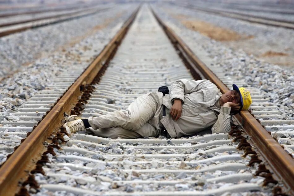 Уставший с долгой дороги отец решил отдохнуть. Человек на железной дороге.