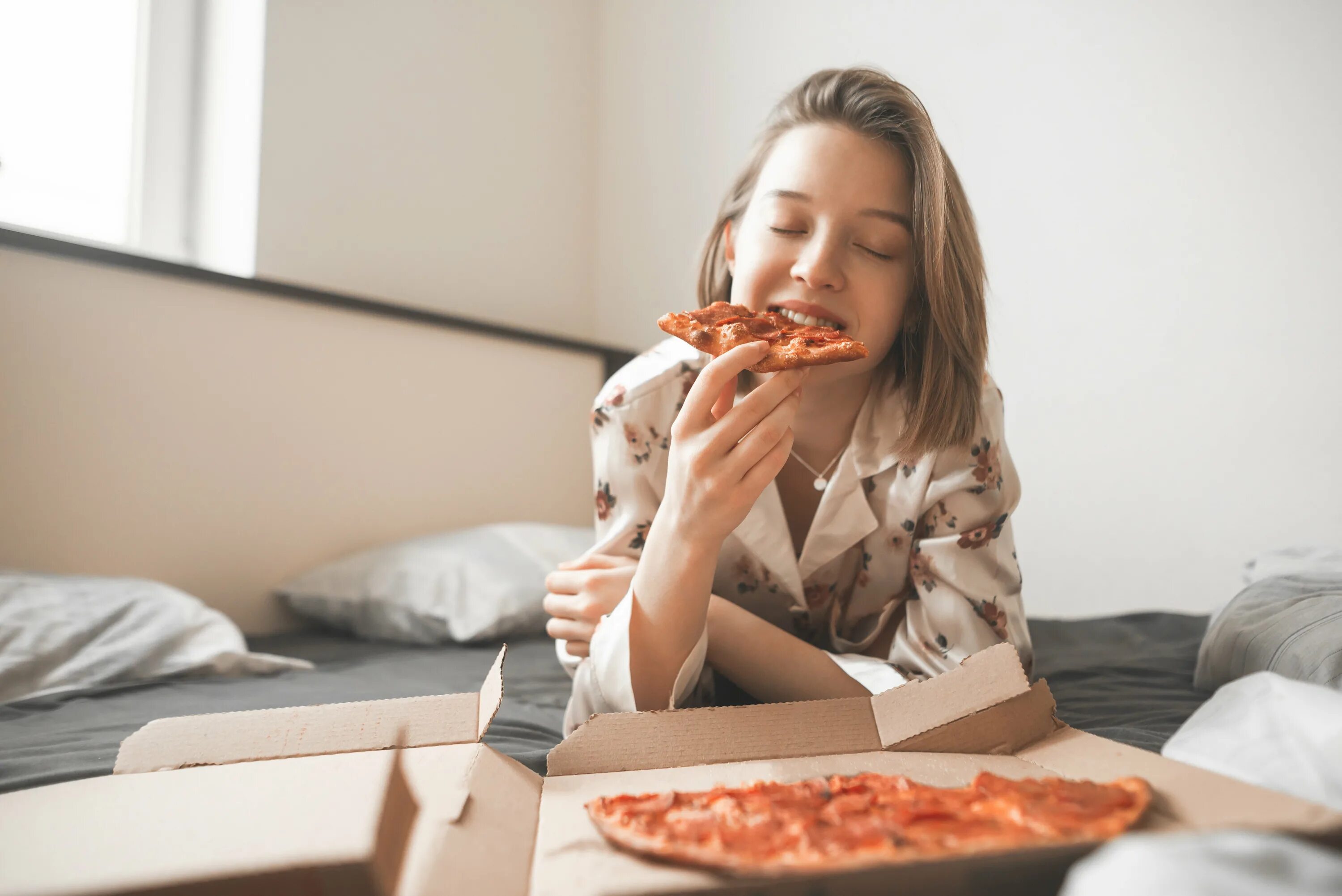 Съесть страдать. Девушка ест пиццу. Девушка с пиццей на диване. Пицца в постели. Девушка с пиццей на постели.