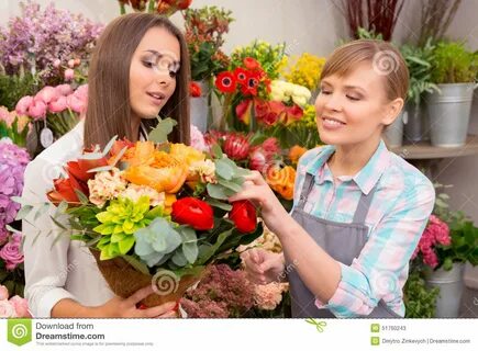 Young cheerful florist showing to customer flowers in bouquet.