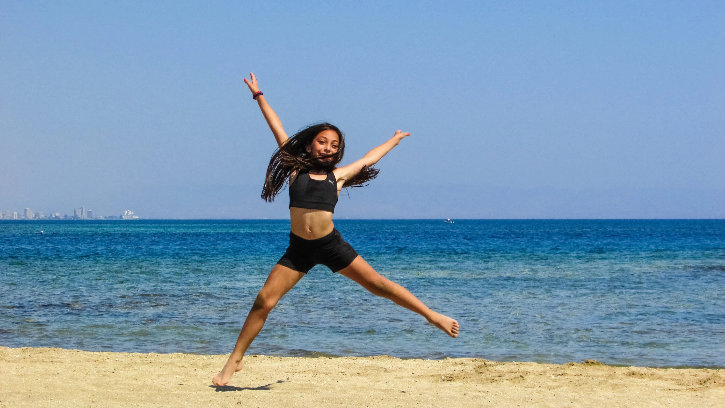 Летние танцы. Девушка танцует на пляже. Гимнастика на море. Танцующая девушка на пляже.