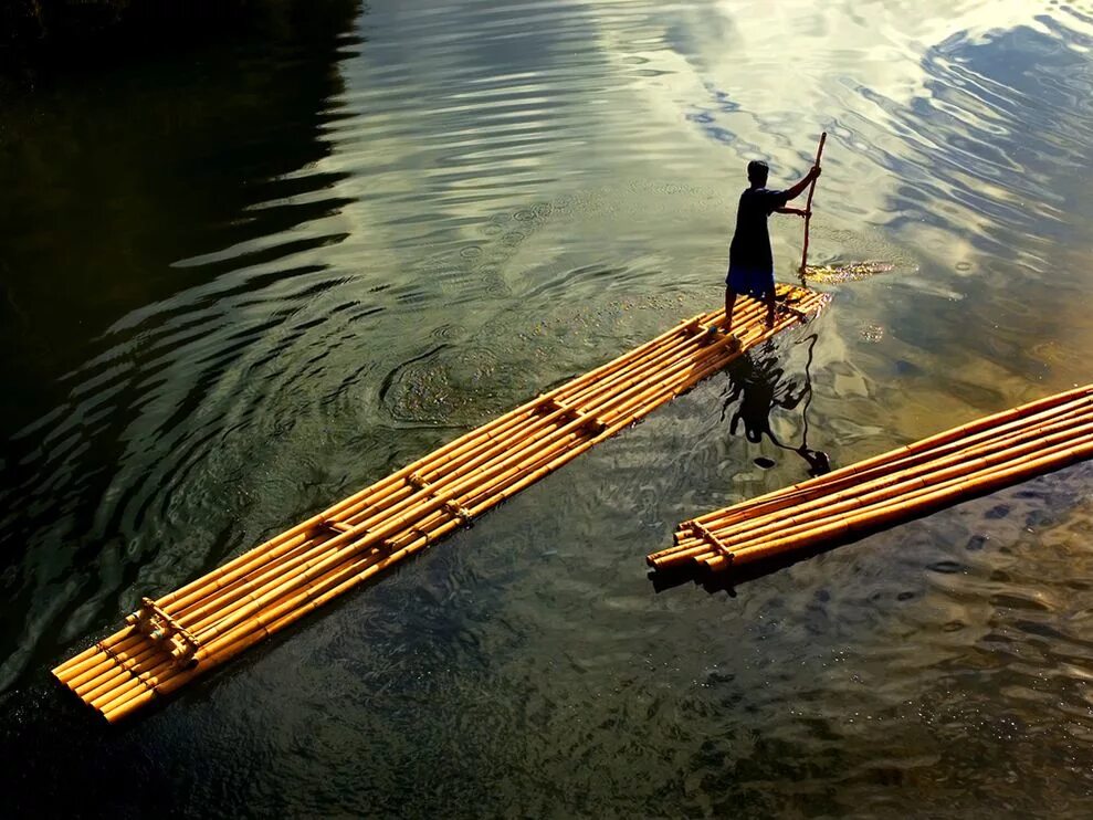 Бамбуковый плот. Деревянный плот. Плавающий плот. Человек на плоту. Рассекая воду плывет по реке